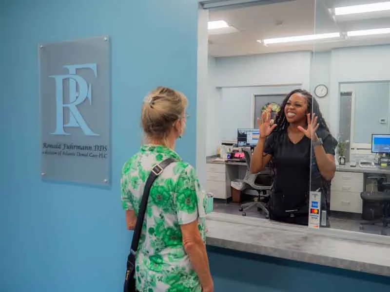 Patient chekcing in at the front desk to discuss dental crown options at Ronald Fuhrmann - Virginia Beach VA.