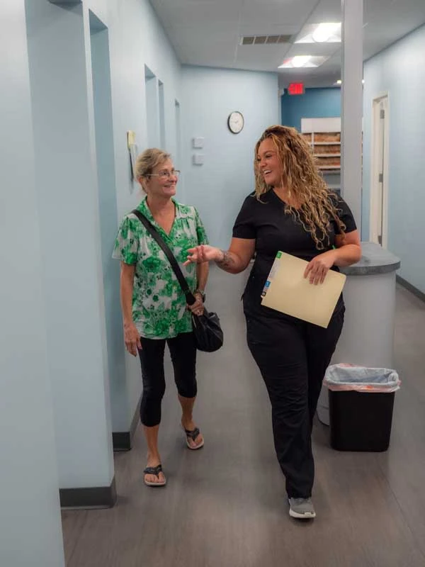 A senior patient walking down the hall with a staff member at Ronald Fuhrmann - Virginia Beach VA.