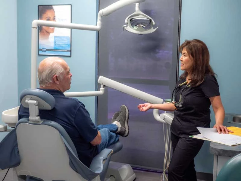 A senior patient sitting in an exam chair ready to discuss dental resotration options with the staff The dedicated dental staff at Ronald Fuhrmann DDS in Virginia Beach, VA .
